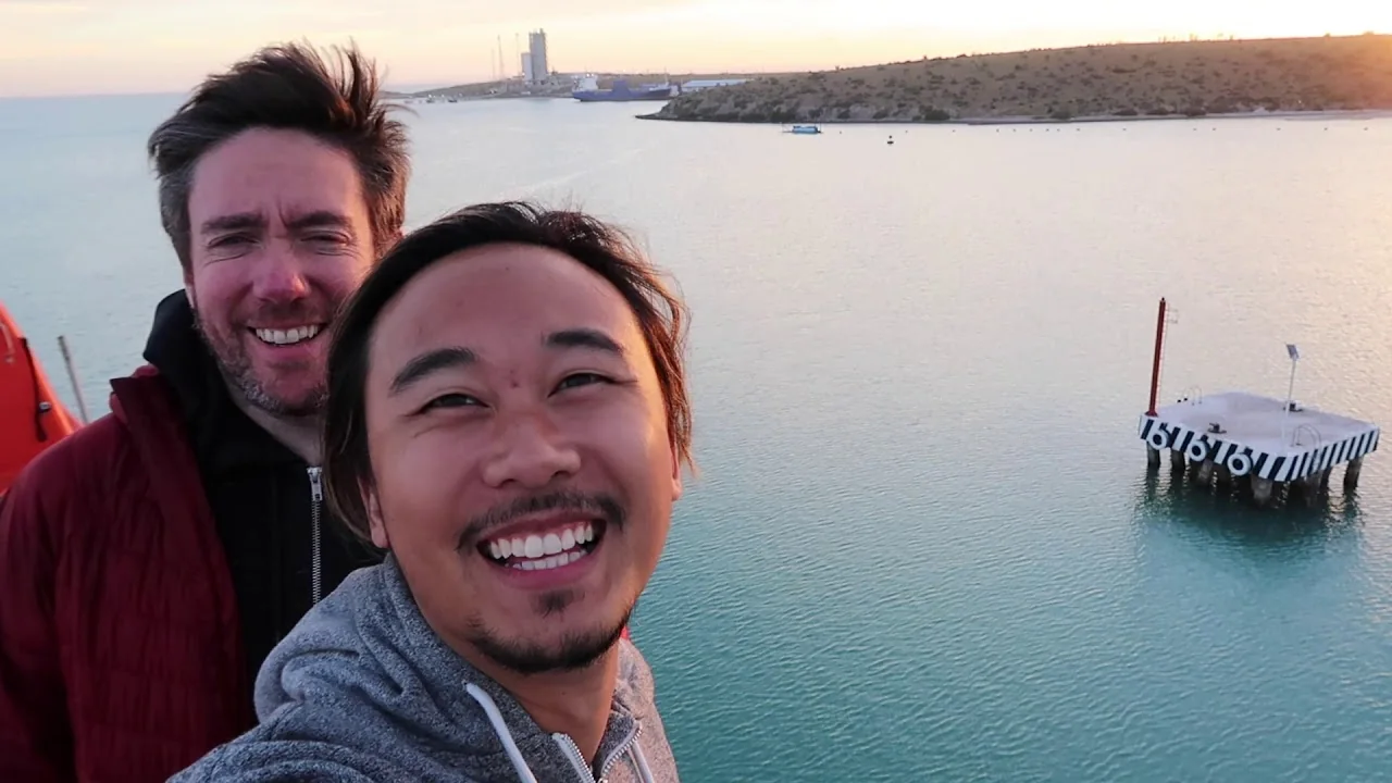 Colin and Nate on a harbour at sunset, from a Sol Chasers video